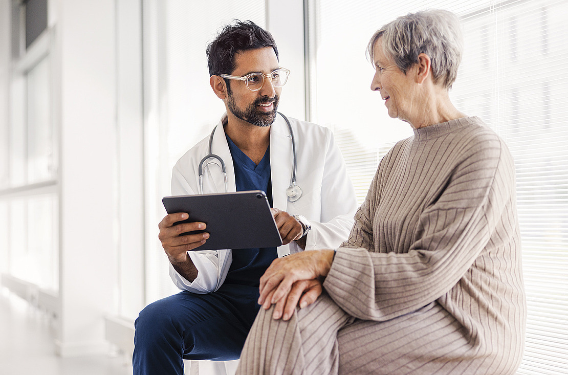 Ein Arzt berät seine Patientin. Er hält dabei ein Tablet in der Hand. Im Text geht es um die elektronische Patientenakte (ePA).