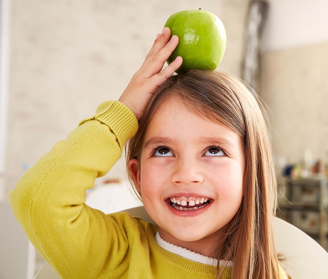 Mädchen balanciert Apfel auf dem Kopf