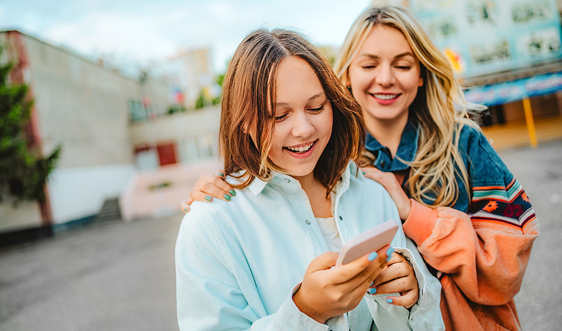 Zwei junge Frauen schauen auf ein Smartphone.