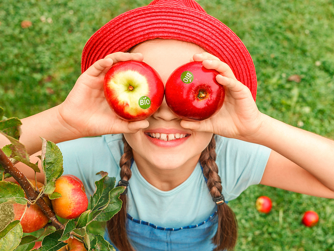 Mädchen mit Äpfeln mit Bio-Etikett