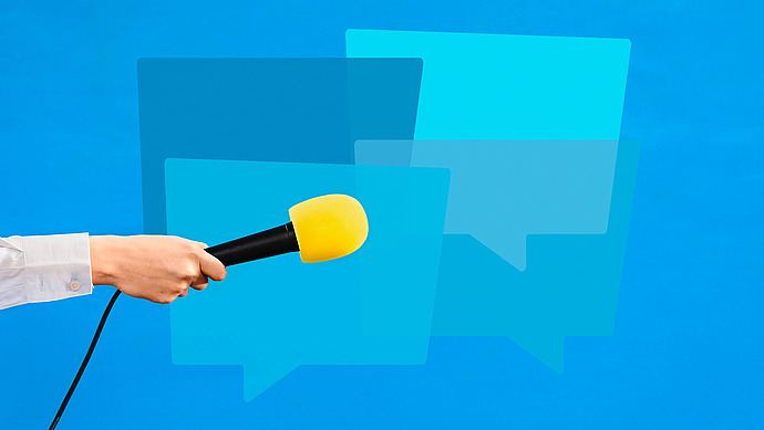 Eine Hand, die ein gelbes Mikrofon hält, ist in Richtung überlappender blauer Sprechblasen auf einem hellblauen Hintergrund ausgestreckt und symbolisiert Kommunikation oder ein Interview.