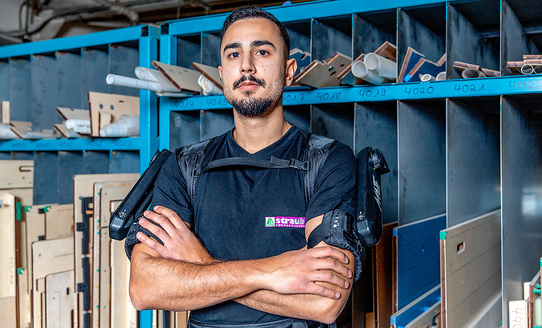 Portrait von Straub-Mitarbeiter Ali Elbasi, der sein Exoskelett trägt. Die Exoskelette sind Teil des Betrieblichen Gesundheitsmanagement (BGM), ein Angebot der vivida bkk.