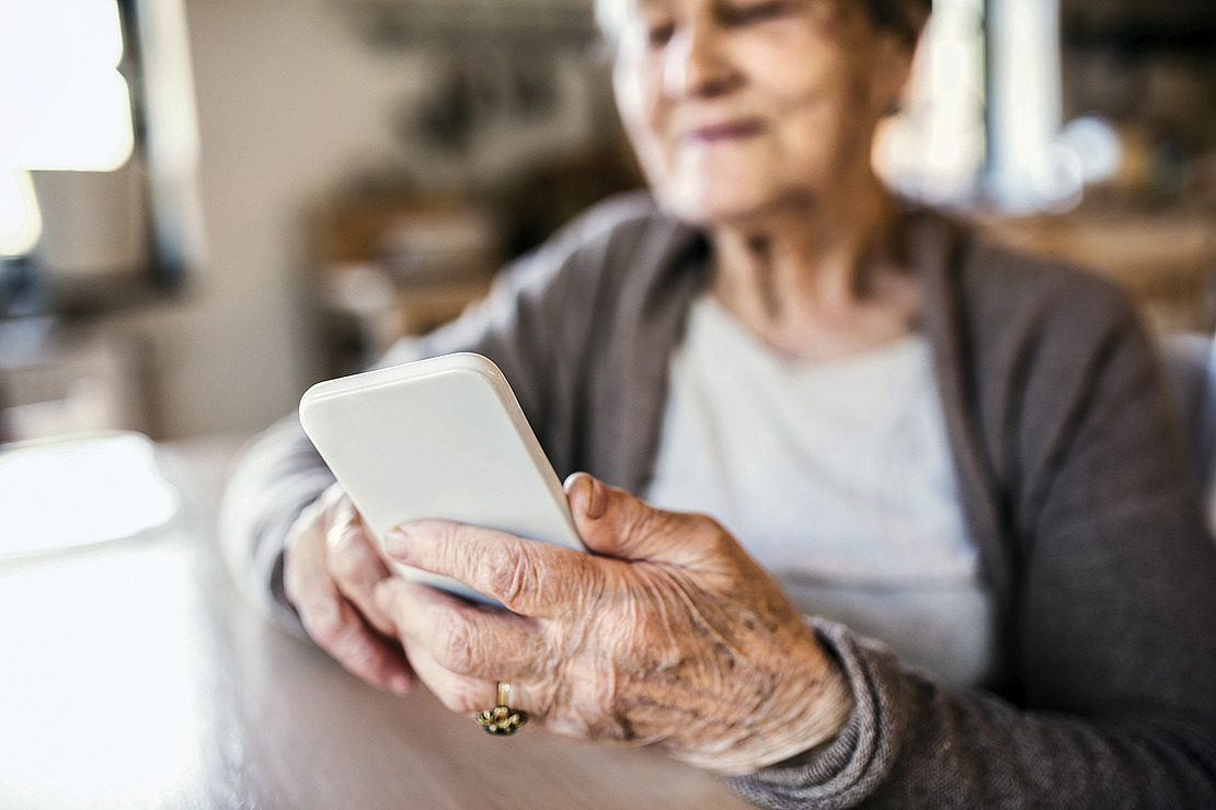 Das Bild zeigt eine ältere Frau, die ein Smartphone bedient. Im Artikel geht es um eine App, die Spastiken nach einem Schlaganfall frühzeitig erkennen kann.