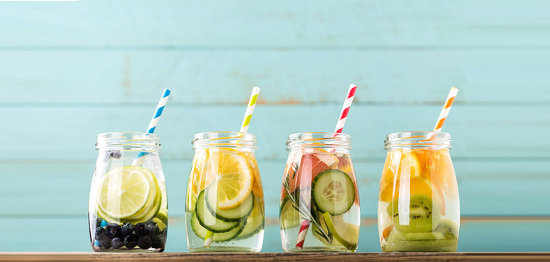 Vier Gläser mit Wasser und Früchten