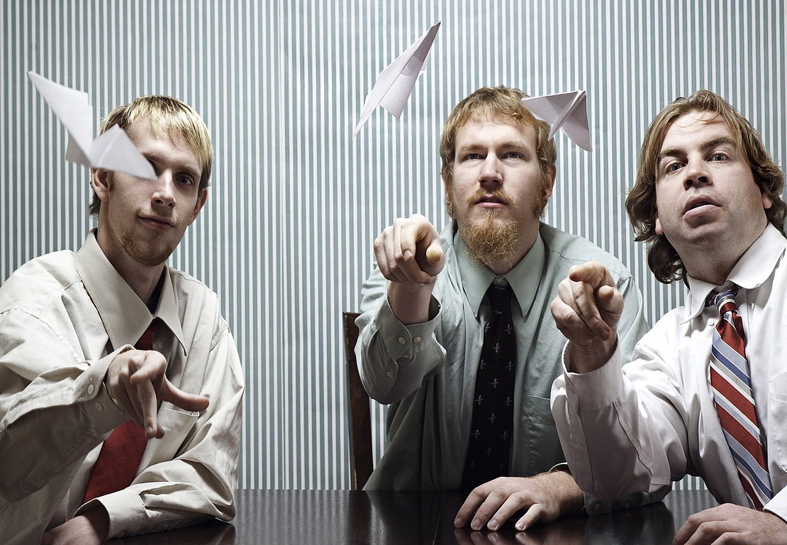 Drei Männer lassen Papierflugzeuge fliegen