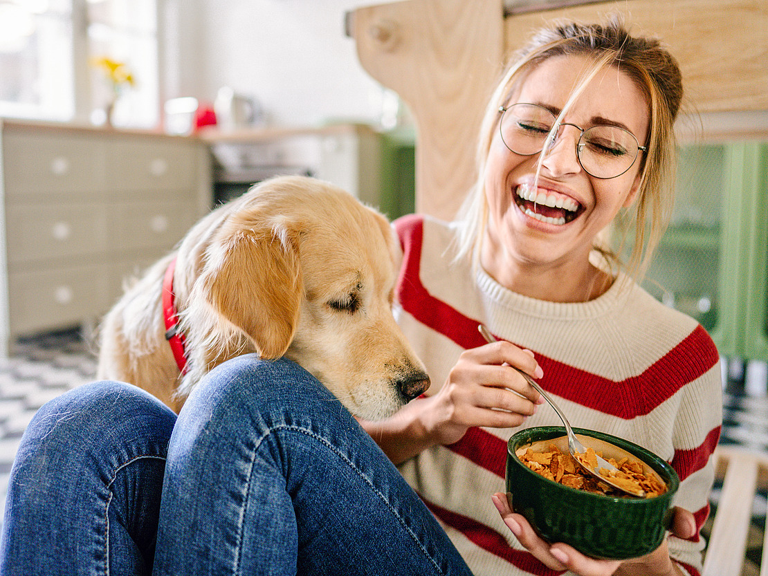 Frau hat beim Essen Spaß mit ihrem Hund