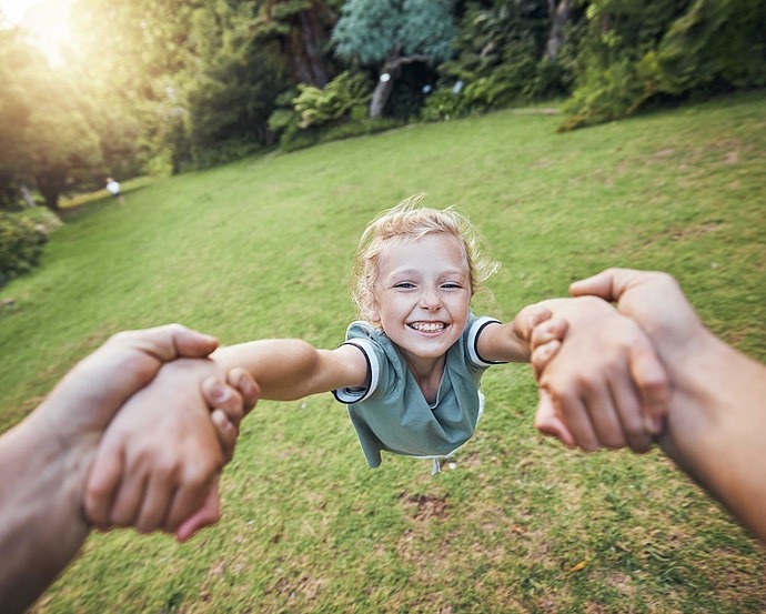 Kind wird mit Händen im Kreis herumgedreht