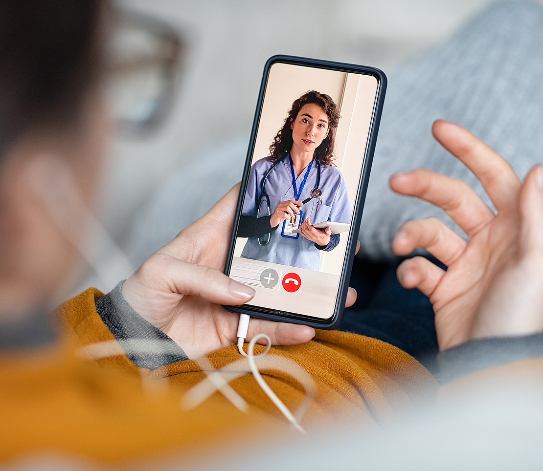 Frau schaut auf ihr Smartphone und nutzt einen digitalen Arztbesuch